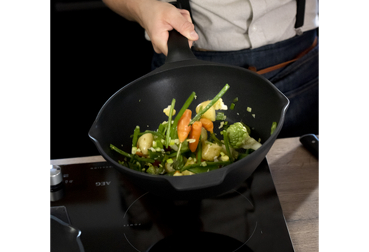 Απεικονίζεται ένα χέρι που κρατάει το τηγάνι στο οποίο υπάρχουν λαχανικά.